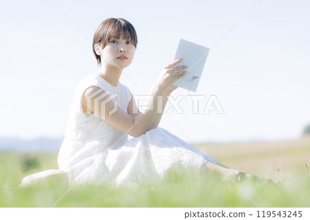 Young woman reading a book in the grass 119543245
