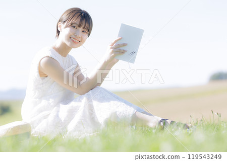 Young woman reading a book in the grass 119543249