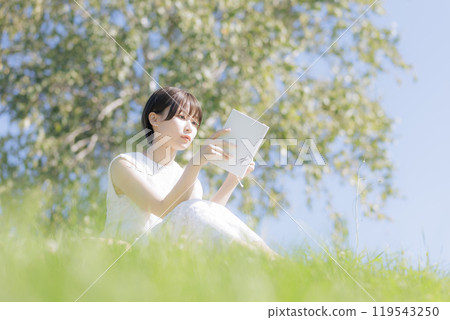 Young woman reading a book in the grass 119543250