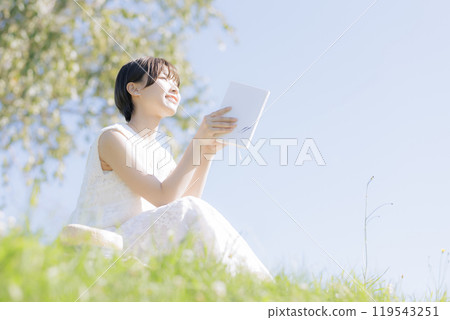 Young woman reading a book in the grass 119543251