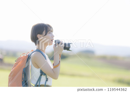 Young woman holding a camera in the grass Young woman holding a camera in the grass 119544362