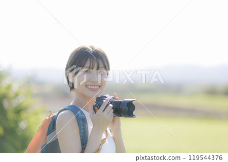 草地上拿著相機的年輕女子 119544376