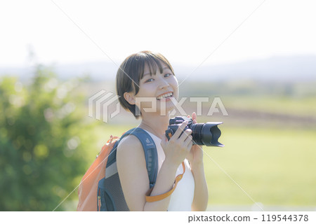 Young woman holding a camera in the grass 119544378