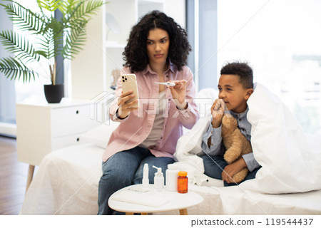 Mother with sick African boy consulting doctor via video call 119544437