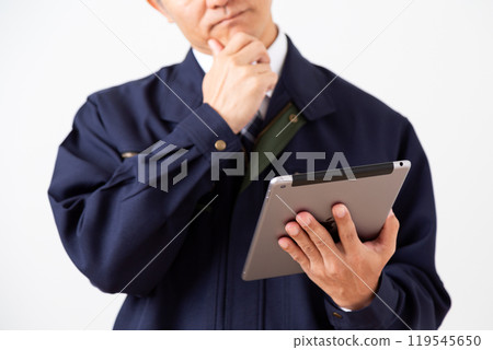 A middle-aged male businessman in work clothes looking at a tablet and worrying 119545650