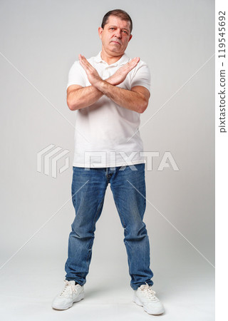 A man making a gesture of refusal with arms crossed against a light background 119545692