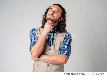 A man with curly hair thoughtfully pondering in a neutral background A man with curly hair thoughtfully pondering in a neutral background 119545704