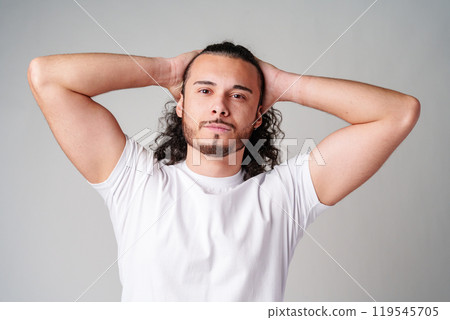 Young man with curly hair poses confidently against a plain background 119545705