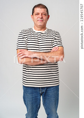 A man stands confidently in a striped shirt, casual jeans with a neutral background A man stands confidently in a striped shirt, casual jeans with a neutral background 119545707