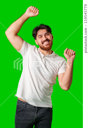 Happy man celebrating success with raised fists, wearing a white shirt against a bright green background 119545779