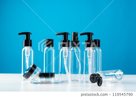 Clear plastic bottles with black caps arranged on a white surface against a bright blue background Clear plastic bottles with black caps arranged on a white surface against a bright blue background 119545790