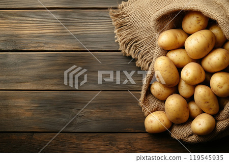 Freshly harvested potatoes spilling from a burlap sack onto a rustic wooden table in a warm, natural Freshly harvested potatoes spilling from a burlap sack onto a rustic wooden table in a warm, natural 119545935