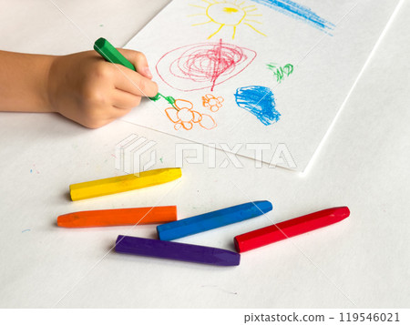 Child drawing with colorful crayons on white paper 119546021