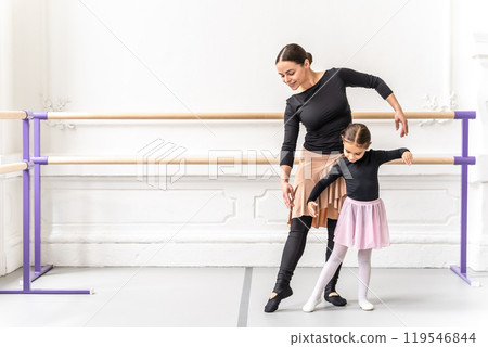 Happy ballerina teacher guiding young student in graceful ballet practice 119546844