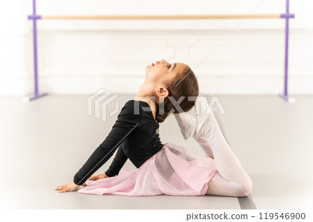 Beautiful little girl practicing ballet on floor in studio stretching 119546900