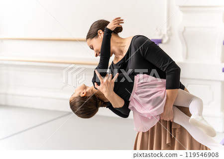 Ballet teacher hugging her young student in studio after creative dance lesson Ballet teacher hugging her young student in studio after creative dance lesson 119546908