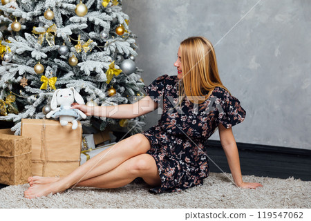 Blonde woman for new year at christmas tree with gifts 119547062