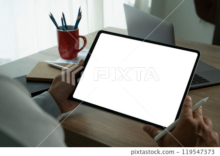 A businessman holds a mockup. iPad digital tablet with blank screen Mockup replaces your design mockup in the office. 119547373