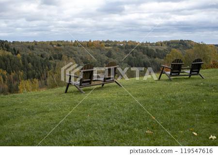Wooden chairs on cabin terrace with mountain view. Chilled Weekend Concept. Garden furniture. Beautiful landscaped backyard with great views. Hills landscape. Lounge armchairs outdoors. 119547616