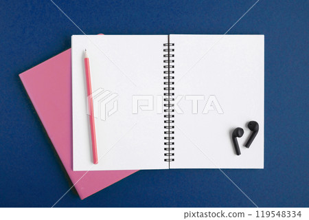 Notebook and pencil, wireless headphones. Open notebook on dark blue color background, spiral notepad. Top view. Notepad with blank white pages for write, office flat lay. Copy Space. Navy. To do list Notebook and pencil, wireless headphones. Open notebook on dark blue color background, spiral notepad. Top view. Notepad with blank white pages for write, office flat lay. Copy Space. Navy. To do list 119548334