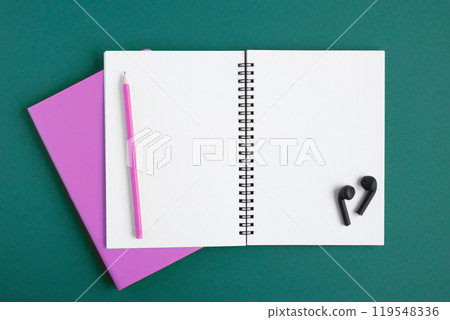 Notebook with pencil, wireless headphones. Open notebook on dark green color background, spiral notepad. Top view. Notepad with blank white pages for write, office flat lay. Copy Space. To do list Notebook with pencil, wireless headphones. Open notebook on dark green color background, spiral notepad. Top view. Notepad with blank white pages for write, office flat lay. Copy Space. To do list 119548336