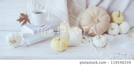 Autumn still life with pumpkins, a cup of coffee, books, candles and autumn leaves on a white wooden background Autumn still life with pumpkins, a cup of coffee, books, candles and autumn leaves on a white wooden background 119548339