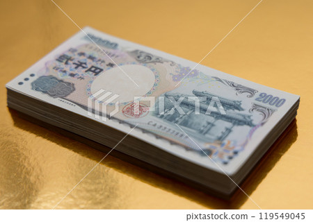 Stack of 2000 yen bills neatly placed on golden surface highlights intricate currency design Stack of 2000 yen bills neatly placed on golden surface highlights intricate currency design 119549045