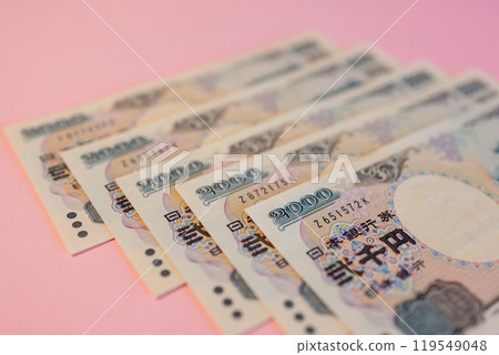 Japanese 2000 yen bills laid out on pink background highlighting detailed currency patterns Japanese 2000 yen bills laid out on pink background highlighting detailed currency patterns 119549048