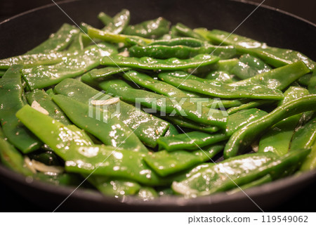 Flat Italian green beans are being sauteed in a pan with garlic and spices Flat Italian green beans are being sauteed in a pan with garlic and spices 119549062