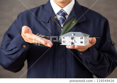 身穿工作服、手持公寓模型的中年男性商人 119549416