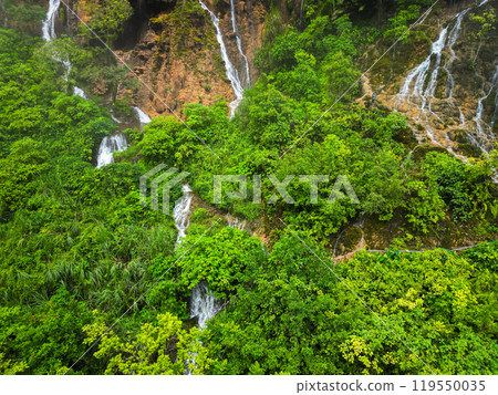 A stunning waterfall located in the center of a lush green forest 119550035
