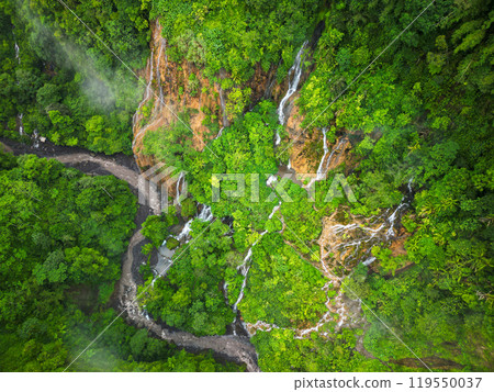 A stunning waterfall located in the center of a lush green forest 119550037