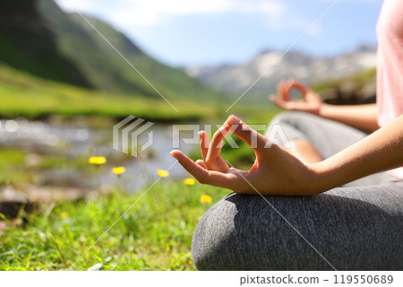 Close up of a woman hands doing yoga in nature 119550689