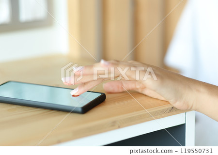 Woman hand stopping alarm on smart phone Woman hand stopping alarm on smart phone 119550731