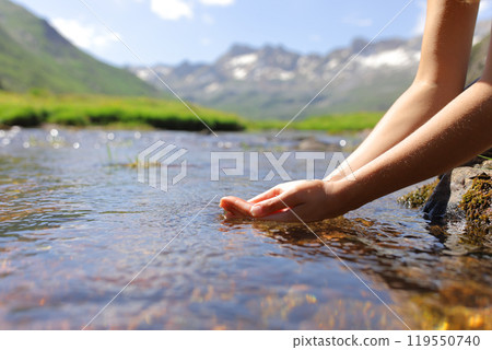 Woman hands catching water from mountain river 119550740