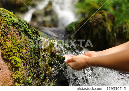 Woman hands in a waterfall catching raw water Woman hands in a waterfall catching raw water 119550745