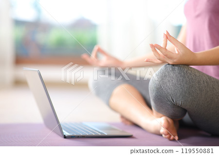Close up of a woman watching yoga tutorial on laptop 119550881