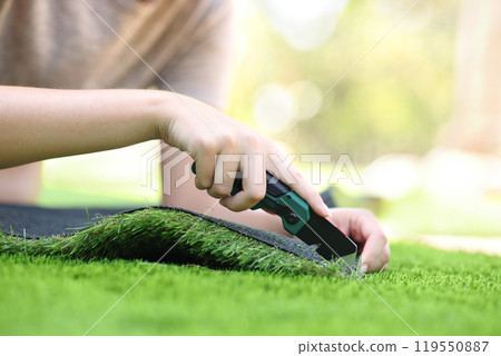 Woman hand cutting and installing artificial grass Woman hand cutting and installing artificial grass 119550887