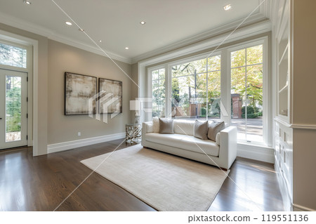 Contemporary living room with natural light, featuring a white sofa, artwork, and wood flooring in a 119551136