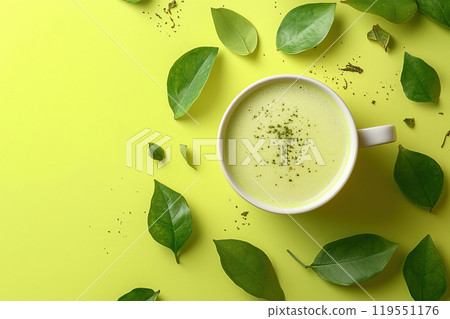 A steaming cup of green tea surrounded by fresh leaves on a bright yellow background in a tranquil 119551176
