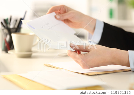Business woman hand putting letter on envelope at the office 119551355