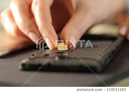 Closeup of woman hands putting sim card on smart phone 119551385