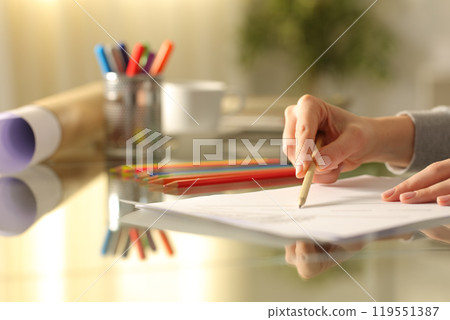 Designer woman drawing with pencil on a desk Designer woman drawing with pencil on a desk 119551387