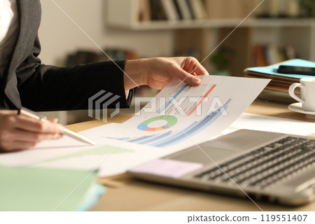 Entrepreneur hands comparing graph reports 119551407