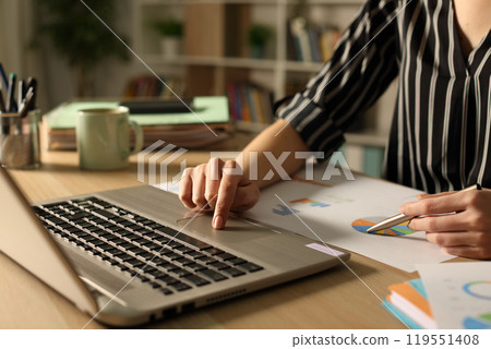 Entrepreneur hands comparing report at night on laptop 119551408
