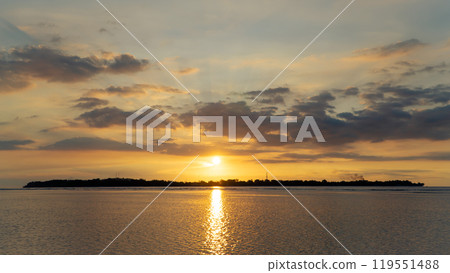 the sun is setting over a small island in the middle of the ocean the sun is setting over a small island in the middle of the ocean 119551488