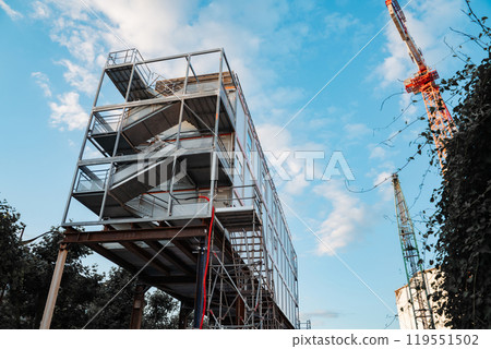 A minimalist urban scene showcasing a construction site with a towering crane. Highlights the intersection of infrastructure, development, and modern architecture under a clear sky. 119551502