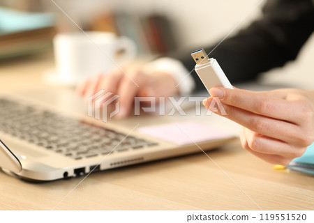 Executive hand holding usb drive using laptop on a desk 119551520