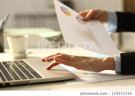 Executive hands comparing report on laptop at night Executive hands comparing report on laptop at night 119551530