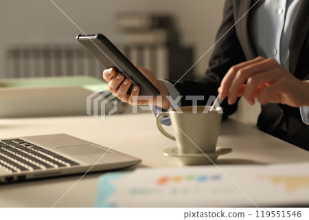 Executive hands stirring coffee checking phone at night 119551546